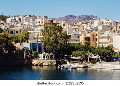 Tradition greek buildings, lake Voulismeni with boats in the center of the coastal town Agios Nikolaos, Crete, Greece