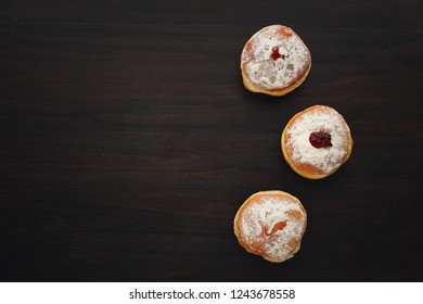 Tradition Jewish Holiday Sweets, Donut Sufganioyt With Sugar Powder And Jam On Dark Wood Background Top View With Copy Space.