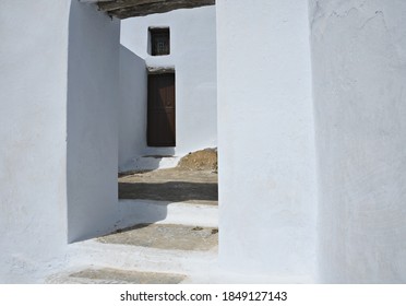 Traditional Adobe Architecture With Whitewashed Walls, Stone Steps And Wooden Door In Amorgos Island, Cyclades Greece. 