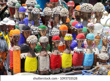 Traditional African Wooden Handmade Dolls With Seashells And Colorful Bead Decoration At Local Craft Market, Cape Town, South Africa. Souvenirs From Africa