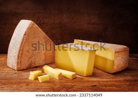Traditional aged mountain cheese of the Alps offered as loaf and piece at a rustic wooden chalet 