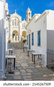 Traditional alley with a narrow street, an exterior of a cafe and a church in Ysternia Tinos island, Greece.