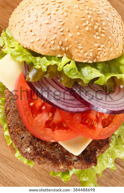 Traditional American cheeseburger. Meat, bun and\
vegetables close up