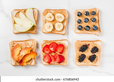 Traditional American and European summer breakfast: sandwiches of toast with peanut butter, berry, fruit apple, peach, blueberry, blueberry, strawberry, banana. White marble table. copy space top view
