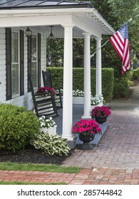 A Traditional American Home With A White Picket Fence And Flag Waving In A Small Town.