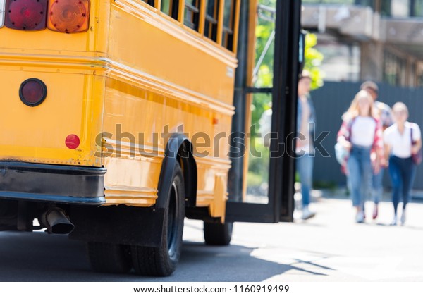 traditional american school bus with group of\
students walking blurred on\
background