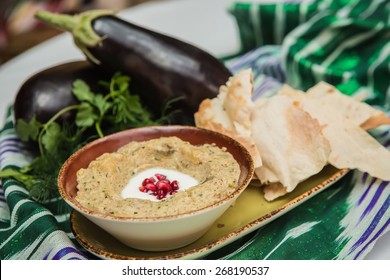 Traditional arabian eggplant dip baba ganoush with herbs and smoked paprika on a wooden background