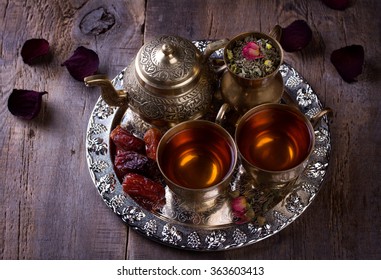 Traditional Arabic Tea Set And Dried Dates. Old Wooden Background