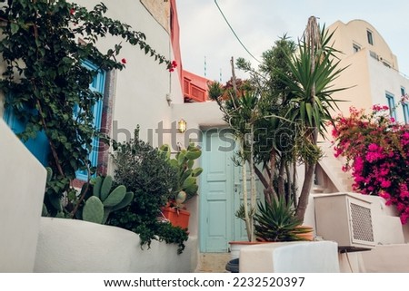 Traditional architecture in Santorini island Greece. White house surrounded with exotic plants, bougainvillea flowers. Exterior with outdoor garden