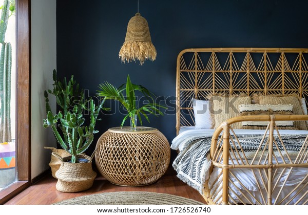 Traditional asian bedroom with ethnic decor,\
lamp over nightstand table, comfortable bed, carpet or rug,\
exotical cactus in basket and natural green plant composition.\
Conceopt of cozy house\
interior