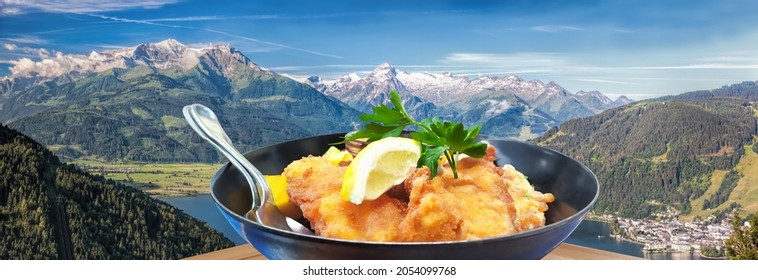 Traditional Austrian Food (Wiener Schnitzel) Over Zell Am See Village With Kitzsteinhorn Peak ( Tauern Alps) In Austria 