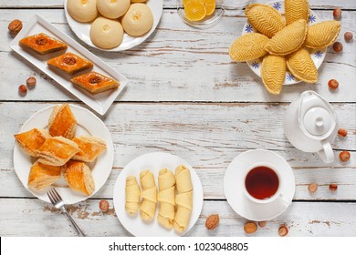 Traditional Azerbaijan holiday Novruz cookies baklava on white plate on the white background with nuts and shakarbura,gogal,sweetbread,tea,lemon,kata,mutaki,flat lay,top view,space for copy 