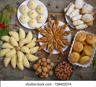 Traditional Azerbaijan holiday Nowruz cookies baklava on white plate on the rustic background with nuts and huzelnuts on green plate and shakarbura,gogal,sweetbread,flat lay