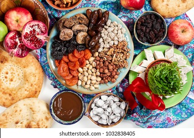 Traditional Azerbaijan sweet cuisine of holiday Nowruz: national dessert called Sumalak, lavash bread, halva, assortment of nuts and dry fruits. Sprouted seeds with red ribbon. Fresh green grass