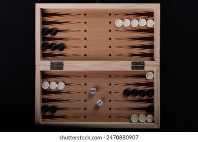 Traditional backgammon game. Photographed from top to bottom. Board with backgammon game pieces on black background.