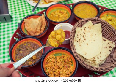 Traditional Bahrain Breakfast Curry Soup In Spoon Of Woman Hand Holding Up In Selective Focus Over Group Of Middle East Bahraini Food Background On Table.