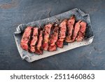 Traditional barbecue dry aged Wagyu rib eye beef steak with salt and pepper sliced and served as top view on a design plate