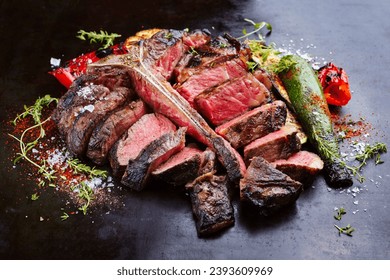 Traditional barbecue dry aged wagyu porterhouse beef steak bistecca alla Fiorentina with grilled vegetable and spice sliced and served as close-up on an old rustic board  - Powered by Shutterstock