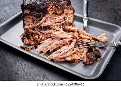 Traditional barbecue pulled pork piece of Bosten butt torn to bits as close-up on a board 