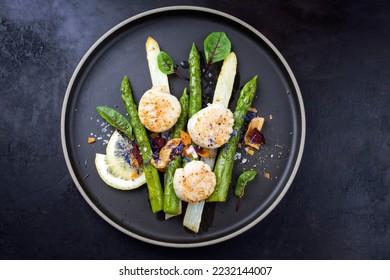 Traditional barbecue scallops with green and white asparagus offered as top view on a modern design plate with copy space  - Powered by Shutterstock