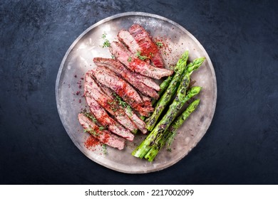 Traditional Barbecue Sliced Dry Aged Wagyu Flank Steak Offered With Green Asparagus And Chili Powder Offered As Overhead View On A Rustic Modern Design Plate With Copy Space 