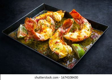 Traditional barbecue spiny lobster tail sliced and offered with saffron lemon sauce as closeup in a metal tray 