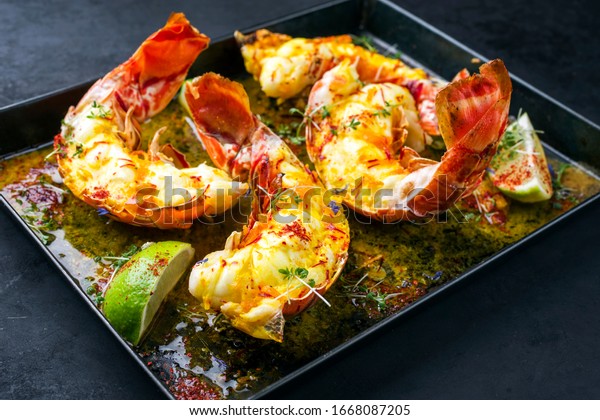 Traditional barbecue\
spiny lobster tail sliced and offered with saffron lemon sauce as\
closeup in a metal try\
