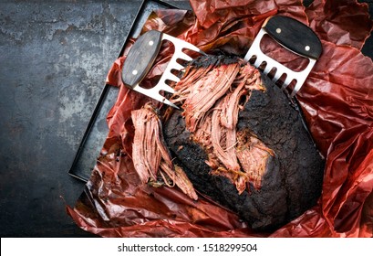 Traditional Barbecue Wagyu Pulled Beef In Peach Paper As Top View With Meat Claws On A Rustic Board