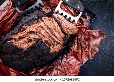 Traditional Barbecue Wagyu Pulled Beef In Peach Paper As Top View With Meat Claws On A Rustic Board