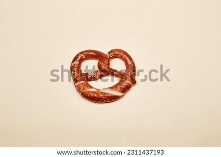 Traditional Bavarian beer snack pretzel baked bun isolated on the bright solid fond plain yellow background