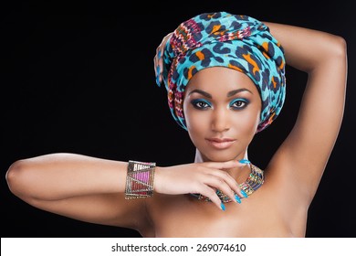 Traditional Beauty. Beautiful African Woman In Headscarf And Jewelry Posing Against Black Background And Looking At Camera