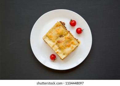 Traditional Beef Lasagne On A White Round Plate On Black Background, Top View. Flat Lay. From Above.