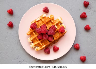 Traditional Belgian Waffle With Raspberries On Pink Plate Over Gray Surface, Overhead View. From Above, Flat Lay.