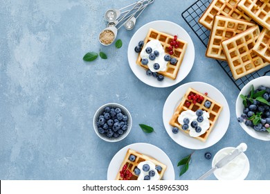 Traditional belgian waffles with cream cheese and fresh blueberry on blue background, top view