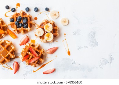 Traditional belgian waffles with fresh fruit and caramel on white background. Flat lay, top view, copy space.