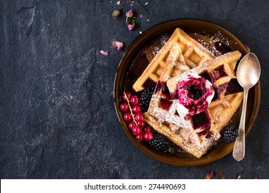 Traditional Belgian waffles with ice cream and berry fruit sauce in the plate,selective focus and blank space