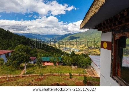 Traditional Bhutanese architecture. Scenic view into a valley in Bhutan . Along the whitewashed traditional house wall. A river meanders through the valley of the mountains, small houses on the slope