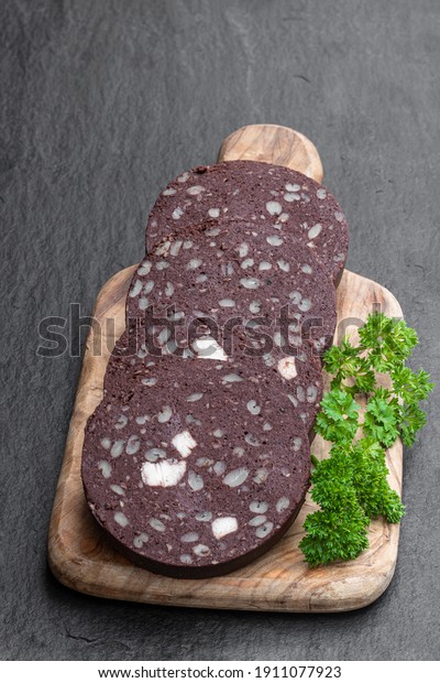Traditional  black pudding sausage slices on black stone\
background 