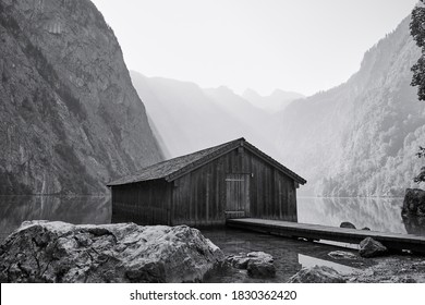 Traditional boathouse at lake Obersee in alpine landscape on a summer morning. Black and white image of a famous travel destination in Schönau am Königssee, Bavaria, Germany.