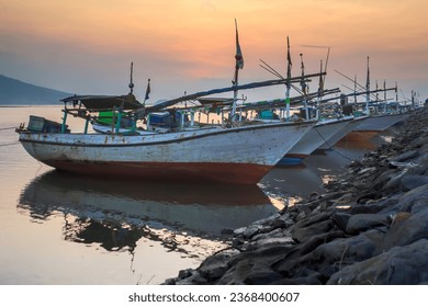 Traditional boats leaning on the pier, at sunset on the coast