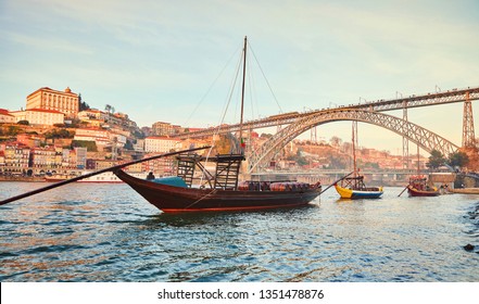 Traditional boats with wine barrels on Douro river in old Porto with background of Dom Luis bridge, Portugal