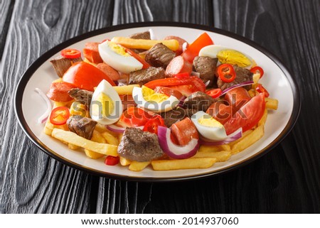Traditional Bolivian cuisine spicy multicomponent Pique macho close-up in a plate on a black wooden background. horizontal

