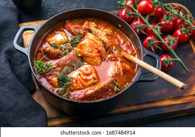 Traditional Brazilian fish stew moqueca baiana with fish filet in tomato sauce as top view in a modern design cast-iron roasting dish 