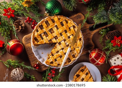 Traditional British Christmas mince pie. Homemade sweet mincemeat tart cake, filled with spiced dried fruit, nuts and apples, on cozy wooden table with  with Christmas tree and decoration - Powered by Shutterstock