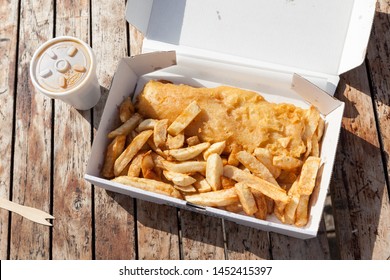 Traditional British Fish and Chips in a Box on a Wooden Table.