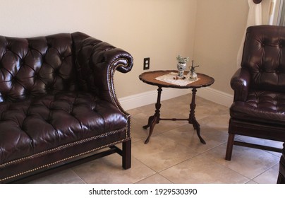 Traditional Chesterfield sofa couch and armchair with a small vintage round table.