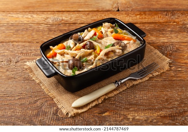 Traditional chicken stew with\
mushrooms and vegetables. Chicken casserole. Served in black\
pots.