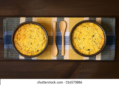 Traditional Chilean Pastel de Choclo corn pie in rustic bowls, photographed on dark wood with natural light. Below the corn-basil mix is ground meat, olive, boiled egg, raisin, pieces of chicken.    - Powered by Shutterstock