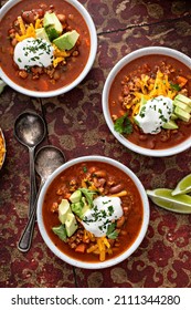 Traditional Chili Soup With Meat, Vegetables And Red Beans In White Bowls With All The Toppings