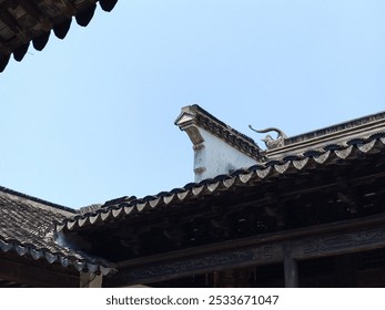 Traditional Chinese architectural roof details with ornate carvings against a clear blue sky. - Powered by Shutterstock